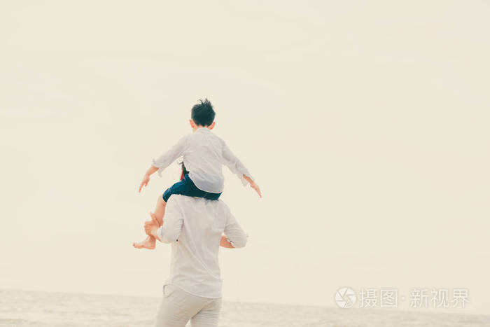快乐的父亲在夏天的热带沙滩上背着儿子的脖子上