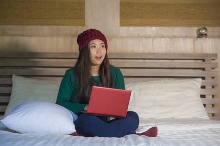 生活方式坦诚的家庭肖像年轻美丽和快乐的亚洲女孩在冬天豆豆坐在床上放松使用笔记本电脑享受乐趣享受在线电影或社交媒体