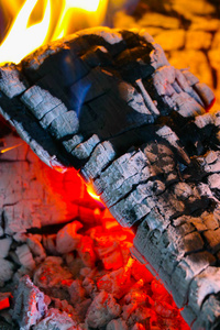明亮多彩的火焰, 在壁炉燃烧的木材。柴火砖在火上, 特写镜头。手与木日志