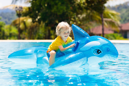 与充气鲨鱼男孩孩子们在游泳池里玩耍.孩子们学习游泳.