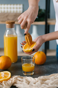 妇女的手挤压新鲜橙汁在玻璃早餐
