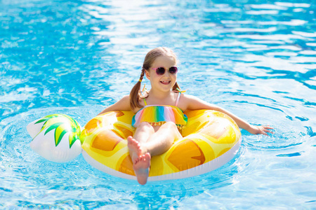 儿童戒指带充气菠萝玩具戒指的孩子漂浮在游泳池里.