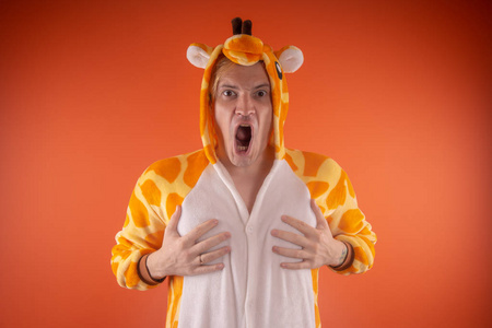长颈鹿的形式的睡衣。一个橙色背景上的人的情感肖像。疯狂和有趣的人在西装。儿童聚会的动画师