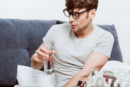 选择焦点的年轻人在眼镜饮用水在床在家里