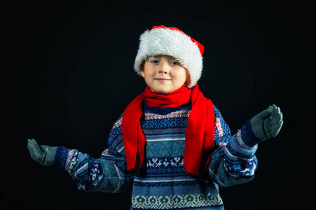 一个开朗的男孩的工作室肖像。这孩子穿着暖和的针织毛衣和帽子。