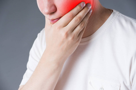 男子牙痛的灰色背景, 痛苦的区域突出显示红色