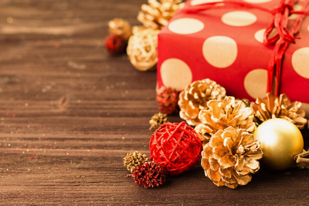 圣诞节和元旦装饰, 金球和冷杉锥, 木星与礼物包裹在红色纸与金黄圈子在棕色木头背景。复制文本的空间