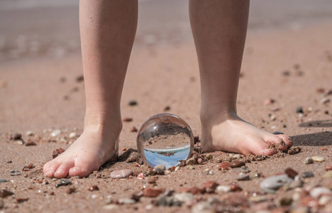 鹅脚小男孩赤脚脚踩在海滩上的鹅卵石上, 反映了黑山 sveti stefan