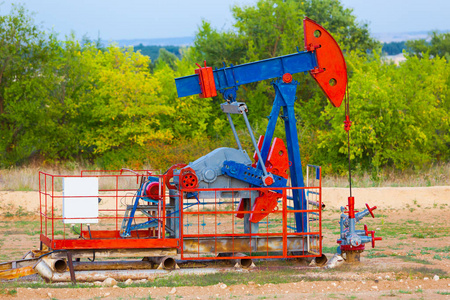 油泵工业设备。油田现场, 油泵正在运行。私营部门石油生产用摇摆机