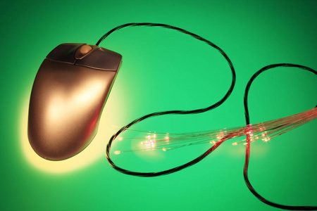 电脑鼠标与绿色背景上的光学纤维