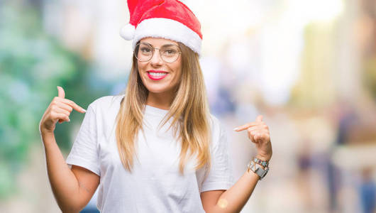 年轻美丽的妇女戴着圣诞节帽子在孤立的背景看自信与微笑在脸上, 指着自己与手指自豪和快乐