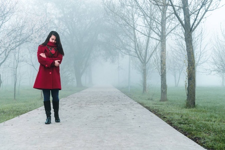 在城市公园在雾中的红色路过的年轻女子