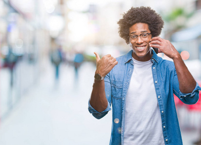 非裔美国人在电话里通过孤立的背景指着和愉快的脸, 用拇指向一边展示