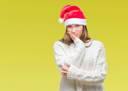 年轻美丽的白人妇女戴着圣诞帽子在孤立的背景下思考看累了, 厌烦与交叉胳膊抑郁症问题