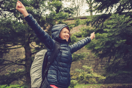 微笑与举的手在森林徒步旅行的学生女士