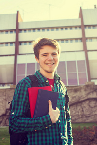 University.Smiling 年轻学生男人抱着一本书和一袋上大学背景