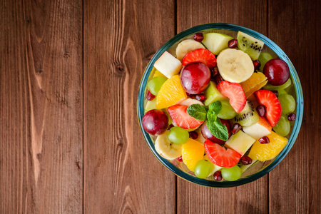 在玻璃碗里木背景上健康的新鲜水果沙拉