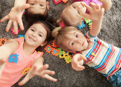 可爱的小孩子玩着五颜六色的数字, 而躺在家里的地毯