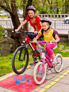 自行车道路标志与儿童。女孩子们穿着头盔带背囊