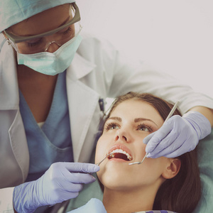女牙医在她病人牙齿工作图片