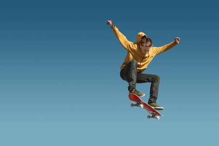 一个少年滑板并奥利捉弄的天空蓝色渐变背景