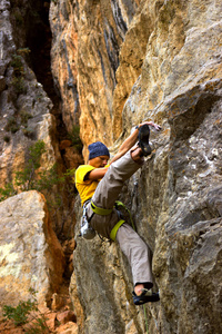 年轻的男登山者，挂在悬崖上用一根绳子