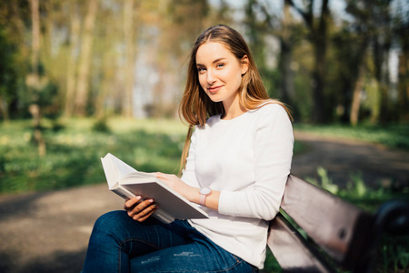 长椅上的书籍大学生在公园长椅上坐着看书照片