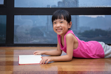 亚洲中国小女孩读一本书靠近窗户旁