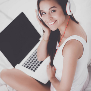 年轻漂亮的女人在床上听音乐