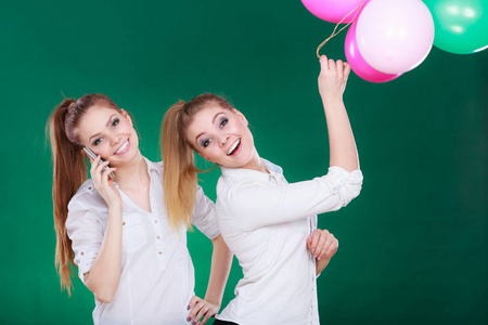 两个女孩子用手机和气球
