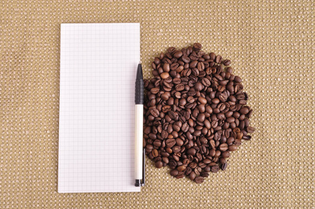 堆的咖啡豆麻布和记事本的背景