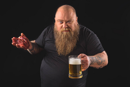 喝啤酒与原料肉的男性胖子
