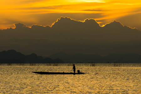 剪影渔夫和湖上的日落天空