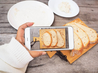 拍照的硬皮面包和烘烤面粉与智能手机