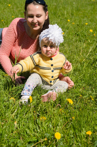 妈妈和女儿坐在绿草，花黄色