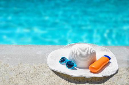 夏天的帽子 墨镜和防晒霜在泳池附近