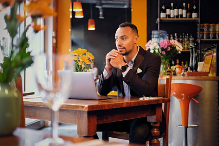 黑人男性在一家餐馆中使用一台笔记本电脑