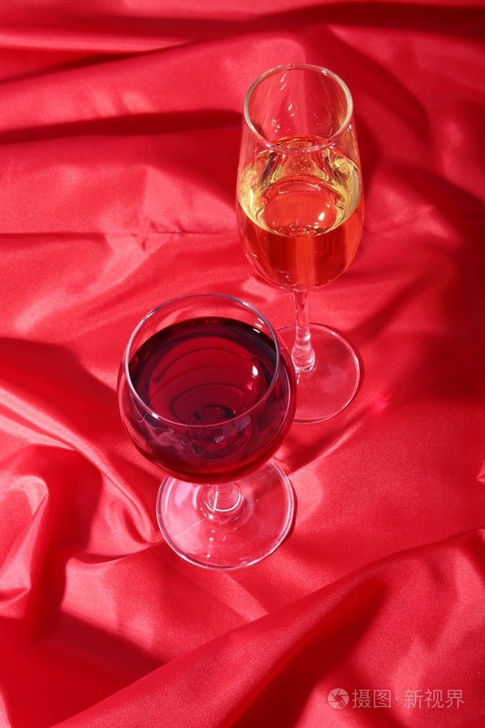 两个玻璃的红, 白葡萄酒在红色背景