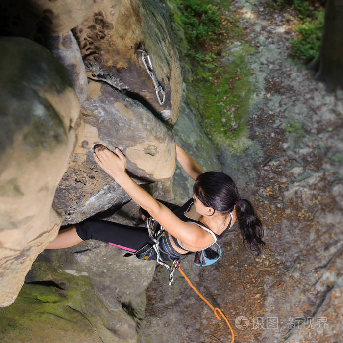 女登山者攀登大石头用绳子的性质