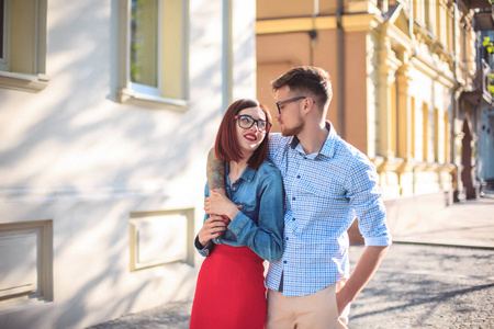 快乐的年轻夫妇站在城里的街上，笑在阳光灿烂的日子