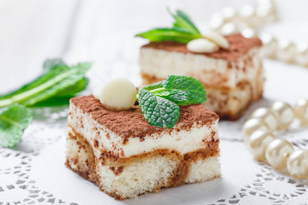 迷你蛋糕提拉米苏与白巧克力，可可和糖果在浅色背景上的关闭。美味的甜点和糖果酒吧