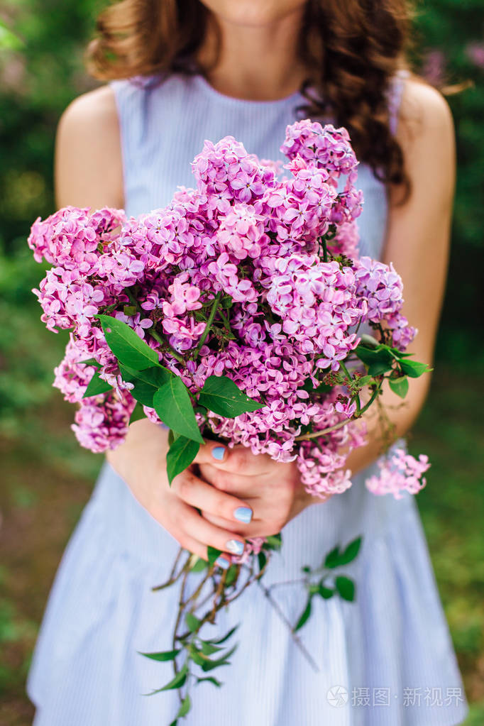 年轻的女孩站在公园背景用束鲜花