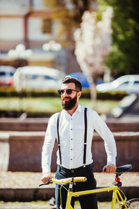 年轻时尚有胡子的人用单手自行车在阳光明媚的大街上