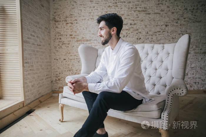 坐在白色的老式沙发上的男人