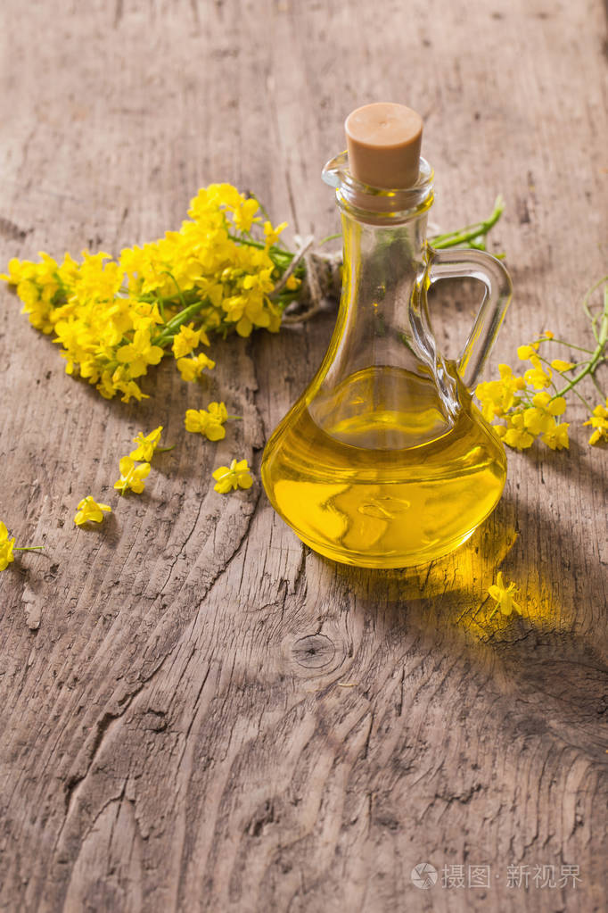 菜籽油 (菜籽油) 和油菜花木制的桌子上