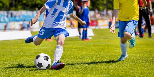 运行青年足球足球运动员。男孩踢足球比赛。儿童足球运动员追球。孩子们运动决斗