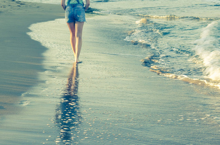 年轻女子走在空荡荡的野生海滩