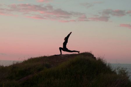 适合女人做瑜伽伸展运动户外在美丽的高山景观。女性的海和日出或日落背景培训 asans 岩石上。女人的瑜伽体式的剪影