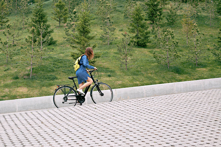 在 zhdinsovom sarafan 上一辆自行车，一个年轻女孩爬上山。城市中的自行车旅游路线