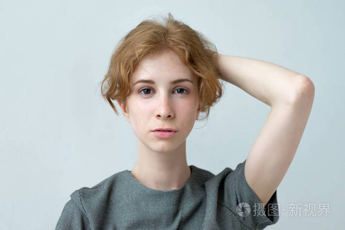 红头发的女孩手里拿着的头发.她穿着灰色